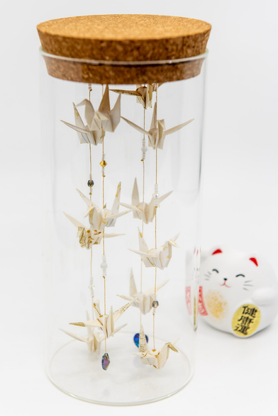 Volière blanche et or en origami dans un bocal un verre