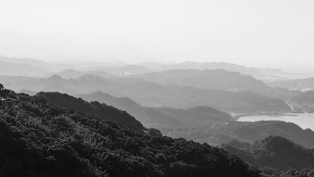 A black and white photograph of a series of mountain ridges getting progressively further from the viewpoint, each getting lighter in shade than the last.