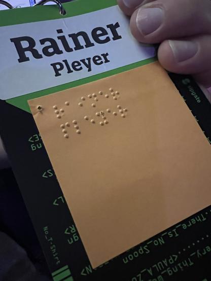 A post-it note with a punched-in name in Braille on a normal name tag