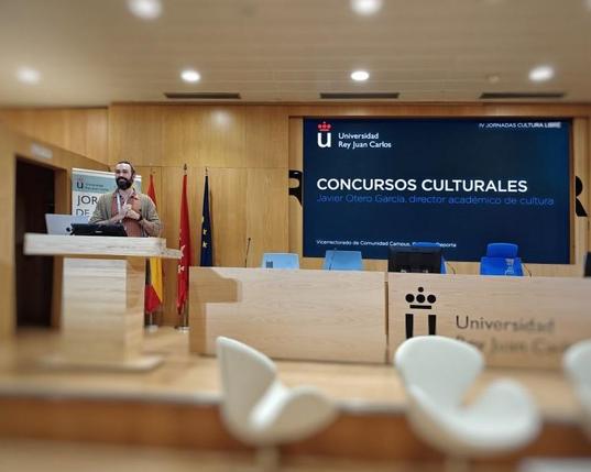 Un hombre en un podio, con una pantalla detrás, listo para hablar ante una audiencia.
