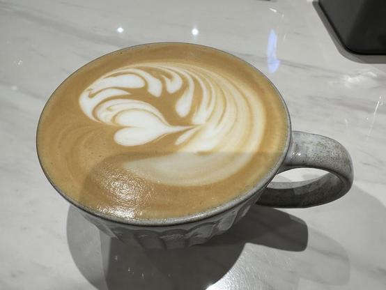 A latte with latte art in a speckled ceramic mug.