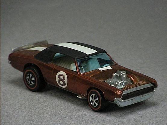 Released in 1970, Spectraflame Brown TNT Bird of 1970 Spoilers with Redline wheels. Notes: Exposed metal engine, roof painted black. Tampo: Numbered sticker, white stripe on top. Packaging: Spoilers. Metal Body, Metal Base. Made in Hong Kong. Scarcity: 6/10