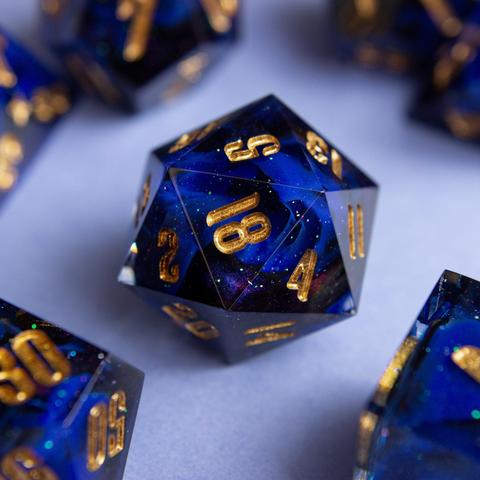 Ein D20 mit goldenen zahlen. Dahinter glitzert es und man sieht einen Farbwirbel aus Ultramarin, Schwarz und colorshifting mica.