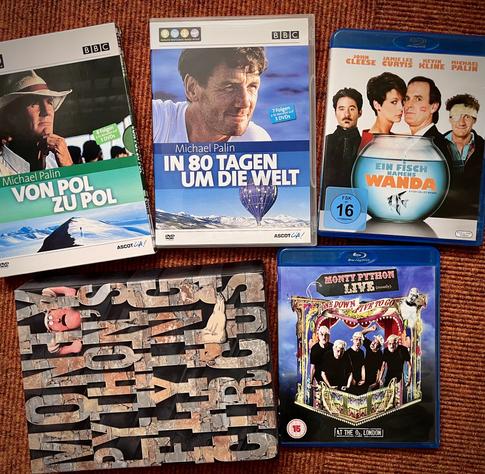 Eine kleine Auswahl meiner DVDs und Blu-Rays von und mit Michael Palin. Zu sehen sind 5 Cover mit Reise- und Comedy-Themen. Zu den Titeln gehören "Von Pol zu Pol", "In 80 Tagen um die Welt", "Ein Fisch namens Wanda", "Monty Python Live" und die Gesamt-DVD-Box zu Monty Pythons Flying Circus.