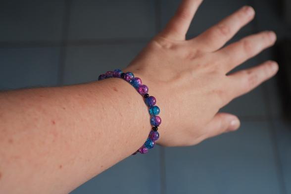 Mon poignet avec un bracelet bleu violet et rose
