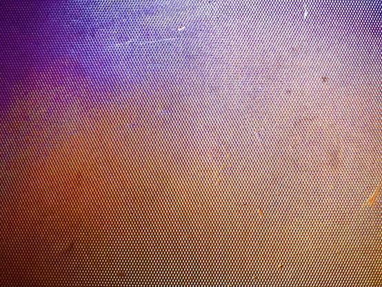 A rigid, bumpy, metallic surface reflects an array of light colors, such as purple, blue, orange, and yellow.