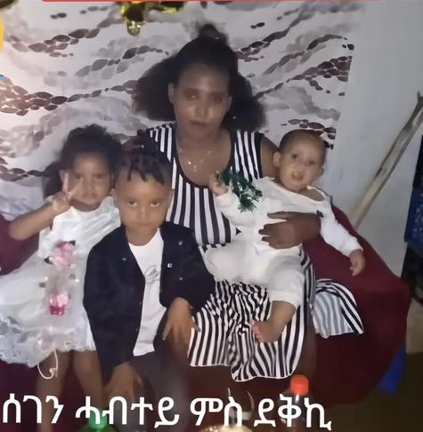 A young Eritrean mother with her three children, she is holding the youngest one on her right side while holding the other two on her left