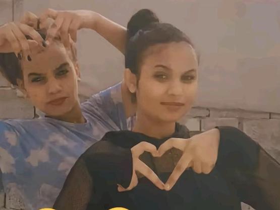Two young Eritrean girls smiling , one of them making a heart sign with her two hands.