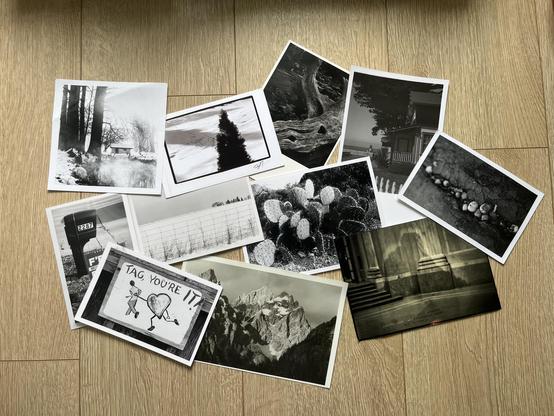 Eleven black and white postcards scattered on the floor.