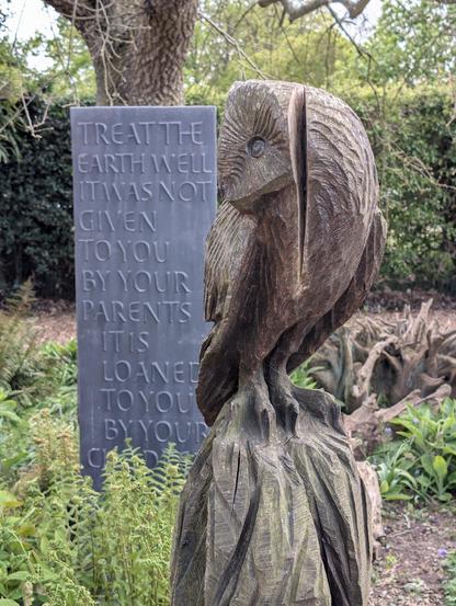 Statue of an owl in front of a plaque saying, "Treat the Earth well. It was not given to you by your parents, it was loaned to you by your children"