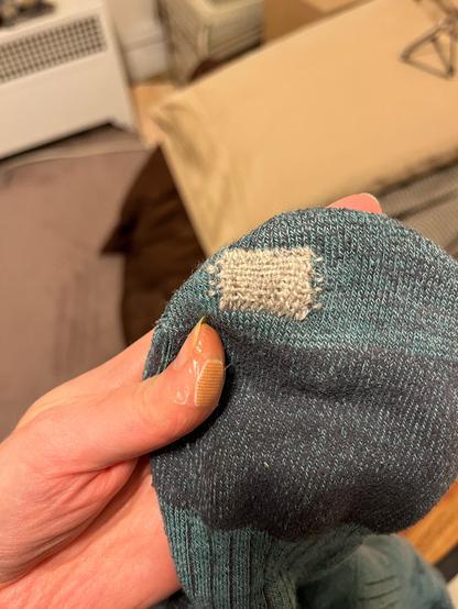 Teal wool sock. A tight woven darn in pale grey covers a hole that mysteriously appeared under the pad of my second toe; likely the work of a moth.