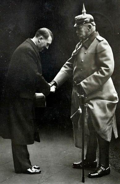 Die beiden Bilder, die du nebeneinander stellst, entfalten in ihrer Symbolik eine tiefgehende, beinahe düstere Parallele, die sich treffend unter das Marx-Zitat stellen lässt:
„Die Geschichte wiederholt sich - das erste Mal als Tragödie, das zweite Mal als Farce."
1. Historisches Bild (1933):
Das erste Bild zeigt den berühmten Handschlag zwischen Paul von Hindenburg, dem greisen Reichspräsidenten, und Adolf Hitler, kurz nach dessen Ernennung zum Reichskanzler am 30.
Januar 1933.
Es markiert einen folgenschweren Moment: Der alte Elitenapparat übergibt einem radikal-populistischen Außenseiter formell die Macht - in der Hoffnung, ihn kontrollieren zu können. Was folgte, war die Tragödie des 20. Jahrhunderts.🖖