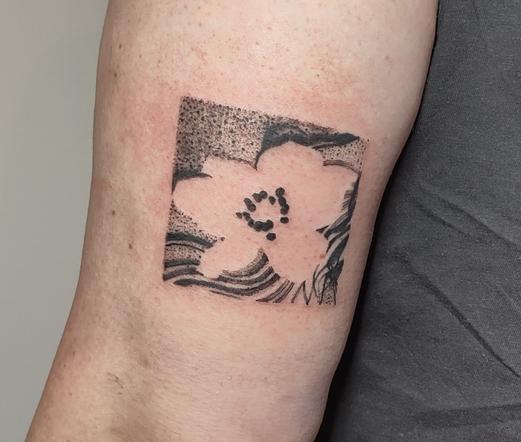 Negative space flower tattoo on the other side of the same upper arm