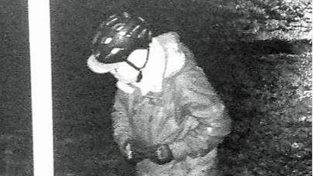 Fahndungsbild der Hamburger Autozei.
Schwarzweiß, eine Person in gebeugter Haltung mit Fahrradhelm, Schrmmütze, Schal und Handschuhen.