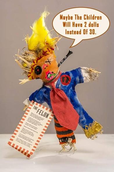 Vudon doll of Trump with a nail in its neck holding a paper with a list of felonies titled The Felon.