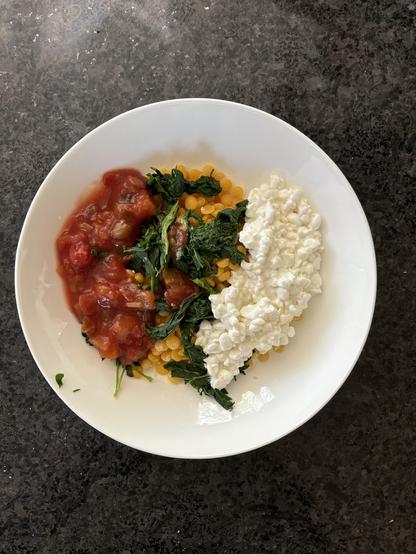 Looking down on my lunch. Bright yellow split peas are topped with bright green cooked nettle leaves in the center arranged in a vertical line with red salsa to the left and white cottage cheese to the right. Colorful, nutritious, vegetarian (could easily be made vegan), and easy!