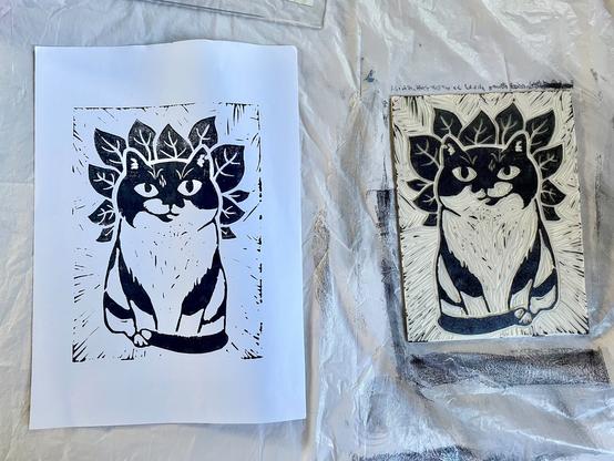 A print of a stout tuxedo cat bsurrounded by basil leaves, next to the cut print block