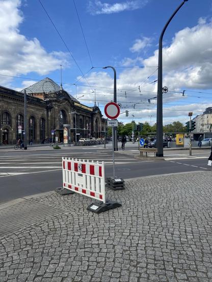 Auf dem gemeinsamen Rad-Fuß-Weg wild abgestellte Baustellenabsperrungen. Im Hintergrund ist der Bahnhof Neustadt zu sehen.