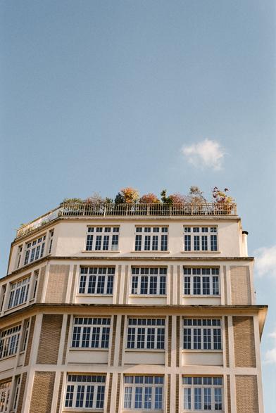 Immeuble parisien, fin de journée, ciel radieux. Des fleurs au balcon, quelques nuages qui n'osent pas vraiment déranger.