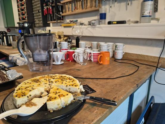 Kuchenbuffet mit einem gezeigten Kuchen und mehreren Tassen auf einer Werkbank in der Werkstatt