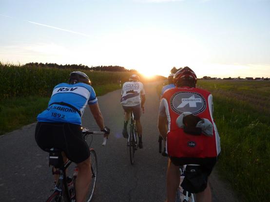 Rennradfahrer auf schmaler Straße in den Sonnenuntergang