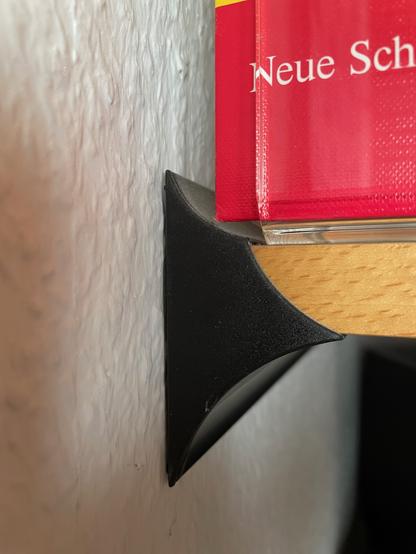 Detailaufnahme der an die Wand geschraubten Schiene. Sie hat ein geschwungenes Profil - kleine Abrundung oben, eine größere unten sowie eine, aus der das Regalbrett hervorsteht.