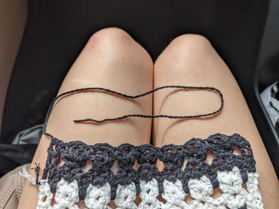 black-and-white tessellated cat scarf ending in a row of black cats, with maybe 14" of yarn left over