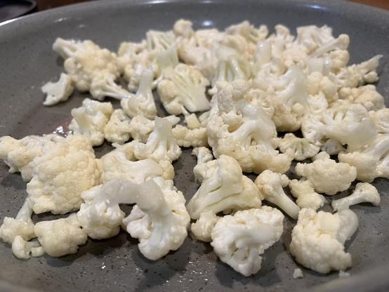 pedazos de coliflor en un sartén que se puede meter al horno