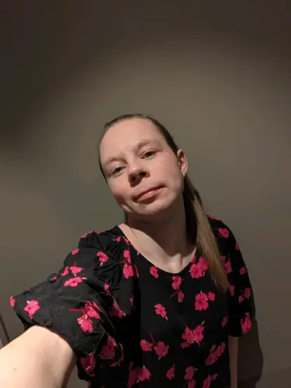 A woman is standing in her apartment, dressed in a floral dress!