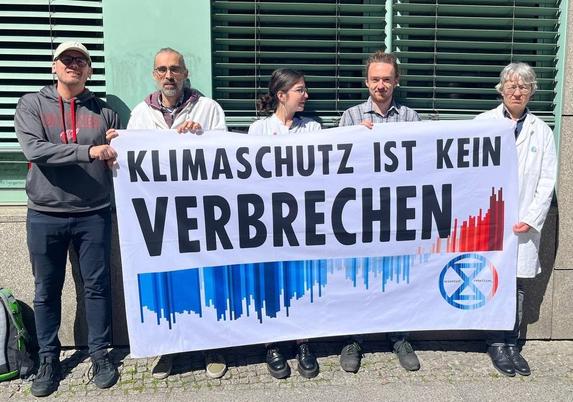 Aktivisten von Scientist Rebellion halten ein Banner "Klimaschutz ist kein Verbrechen"
