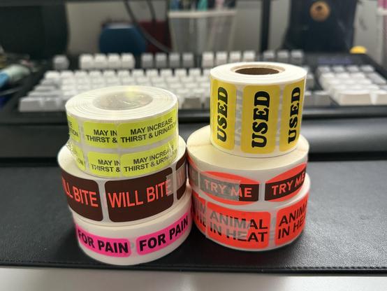 Rolls of labels: ‘May increase thirst & urination,’ ‘will bite,’ ‘for pain,’ ‘used,’ ‘try me,’ ‘animal in heat.’