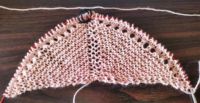 Pink garter stitch in semi-circle, showing first section of eyelet lace