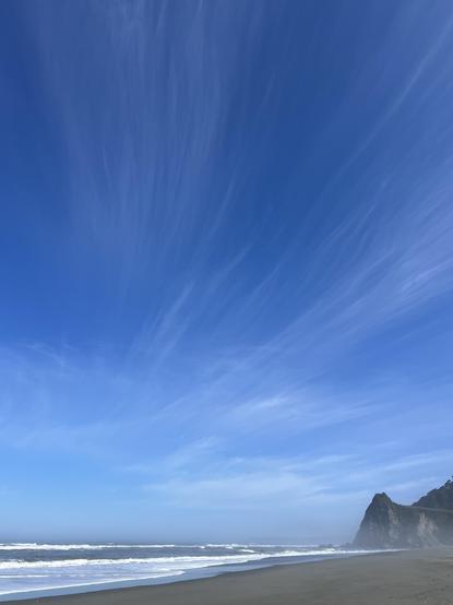 View from the coastal area of Redwood National and State Parks today. The blue sky is a welcome sight. The addition of elegant flowing cloud forms is an added benefit. In the foreground, the Pacific Ocean meets the shore. The point in the distance is about a four mile walk round trip from the closest trailhead.