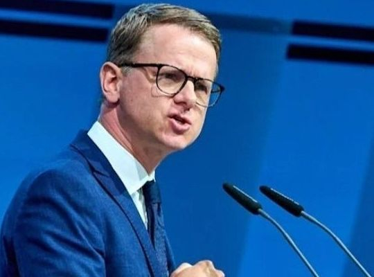 Linnemann mit Hetzfresse, vor  2 Mikrofonen
Anzug: AfD-Blau
Hintergrund: AfD- Blau