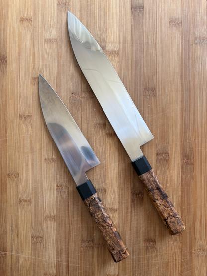 Two kitchen knifes viewed from above on top of a bamboo cutting board