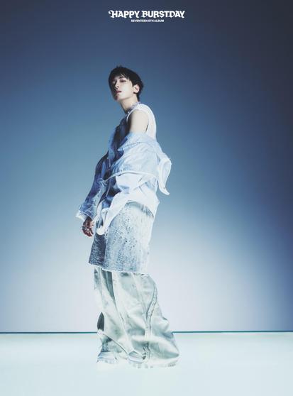 Wonwoo poses in a stylish outfit featuring a layered blue shirt, silver pants, and white sneakers. The background is a gradient from light to dark, enhancing the overall modern aesthetic. The text "HAPPY BURSTDAY SEVENTEEN 5TH album”