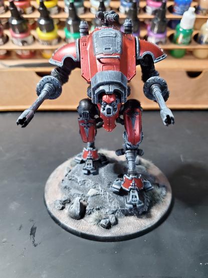 Photo of a primed and partially painted Imperial Knight. Main color is metallic red with black primer dry brushed with white primer underneath.