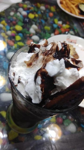 A chocolate milkshake with whipped cream and chocolate syrup.