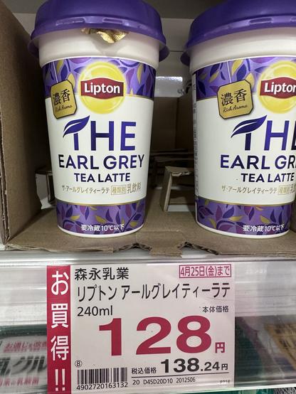 The image features a shelf displaying Lipton The Earl Grey Tea Latte cups. Two cups are visible, each with a purple lid and decorative design. A price tag indicates a cost of 128 yen
