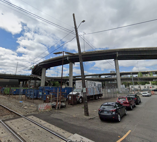 present day photo taken from the nw corner of se 1st and se alder st in portland oregon. the photo is of a vacant lot full of shipping containers. above the vacant lot is one of the ramps leading from interstate 5.
