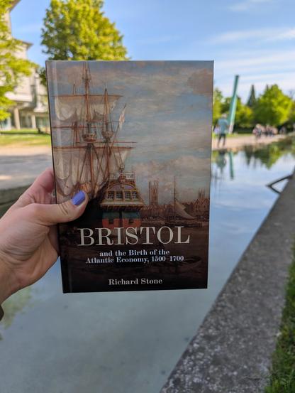 Holding Richard Stone's book "Bristol and the Birth of the Atlantic Economy, 1500-1700" in front of the water course in front of SUB Göttingen