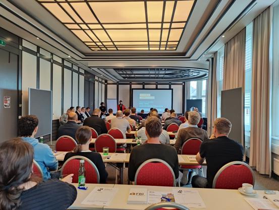 photo of a workshop room with tables .. around 60 people attending, 3 females besides me
