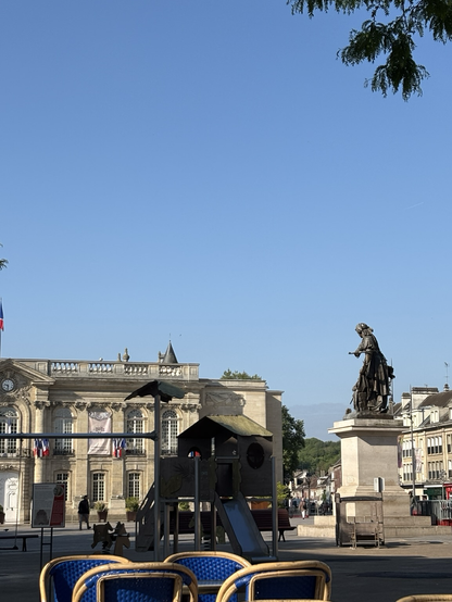 Une place au centre de Beauvais avec l’hôtel de ville (je suppose) au fond, une statut sur la droite (Jeanne hachette ?) et un grand ciel bleu