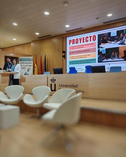 Dos personas presentando un proyecto, hablando frente a una pantalla