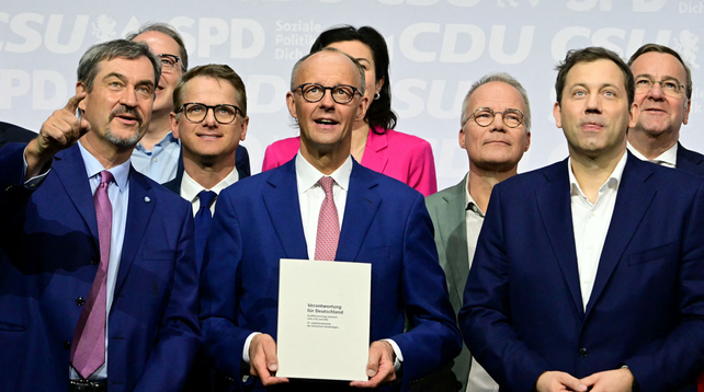 Foto van Duitse politici, je ziet zeven mannen en nog net het roze jasje van een vrouw die achter Friedrich Merz staat.

Het onderschrift van de krant is: CDU-leider Friedrich Merz (midden) presenteert maandag in Berlijn het regeerakkoord. Links van hem CSU-leider Markus Söder, rechts SPD-leider Lars Klingbeil.