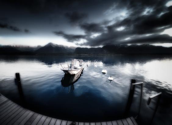 Düsteres Bild vom Thunersee im Berner Oberland mit einem Boot an einem Bootssteg.