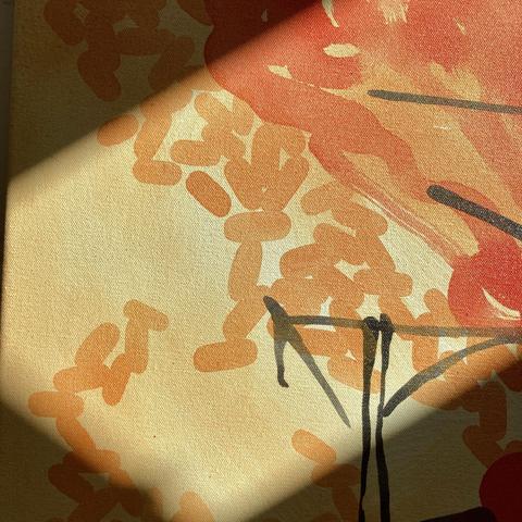 A close-up detail of an acrylic painting on canvas that is illuminated by a sunbeam. The detail is of inky burnt tree branches on a pale orange background, gold-ish swarms of lozenge shapes, and pale red semi-transparent blobs.