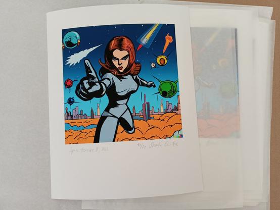 The artist Swaantje Güntzel offers a print which is now available as a limited, numbered and signed edition. The according print which is shown belongs to her series "Space Heroines" which she started in 2022 in the frame of her Artis-in-Science Residence at ESA in Darmstadt. The print shows a heroine in comic style pointing the forefinger of her right hand at the viewer like in the famous Uncle Sam poster. She looks the viewer straight in the eyes. She stands in front of the skyline of a sci-fi like space village, different colourful space objects flying around her. She has red hair and wears a grey jumpsuit covering her whole body. The series was generated with the open source AI DALL·E 2. It is conceived as a commentary on male-dominated space travel Since then, Güntzel has continued to further develop the work, which simultaneously questions the biased practice of AI in which “heroines” are standardized as white, young, slender, mostly blond, scantily clad, over-sexualized women.