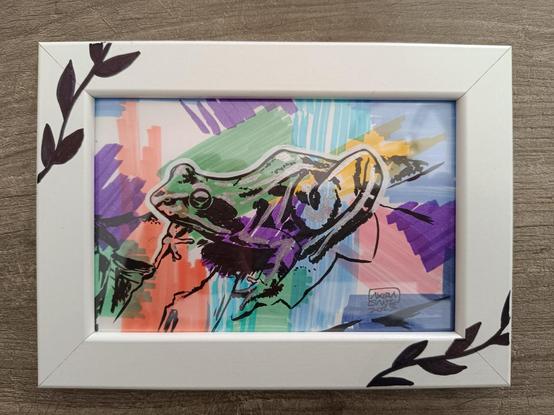 Dibujo a tinta negra y acrílico blanco y dorado con fondo a color a rotulador. El marco es blanco con un par de platas en negro en las  esquinas superior izquierda e inferior derecha.