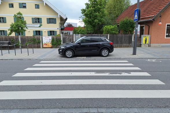 Ein PKW parkt im Bereich eines Zebrastreifens auf dem Gehweg mitten auf dem Blindenleitsystem.